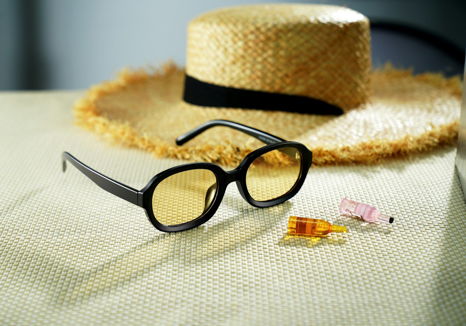 Straw hat and sunglasses with small vials on table