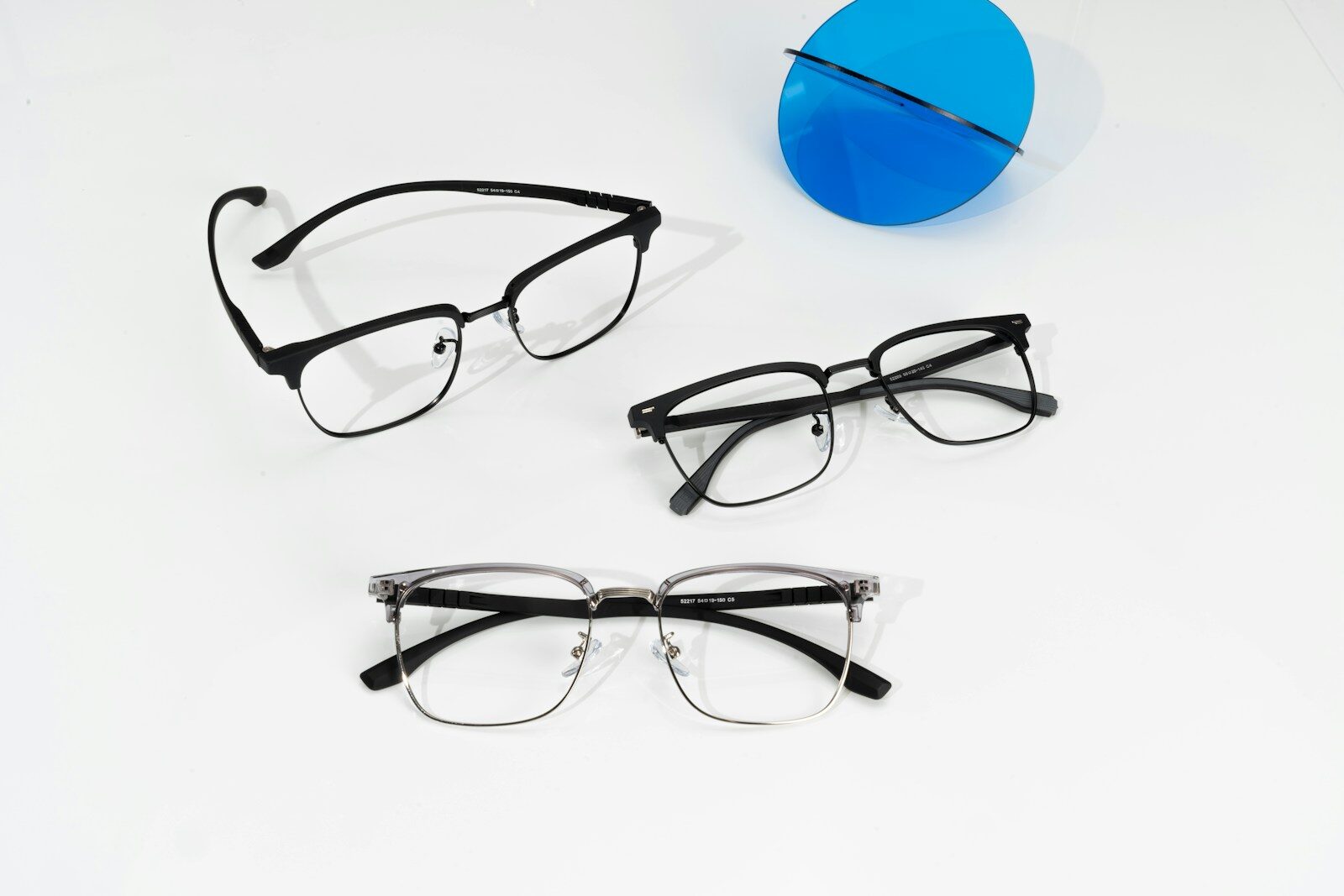 Photo by GlassesShop Three pairs of glasses sitting next to a blue object